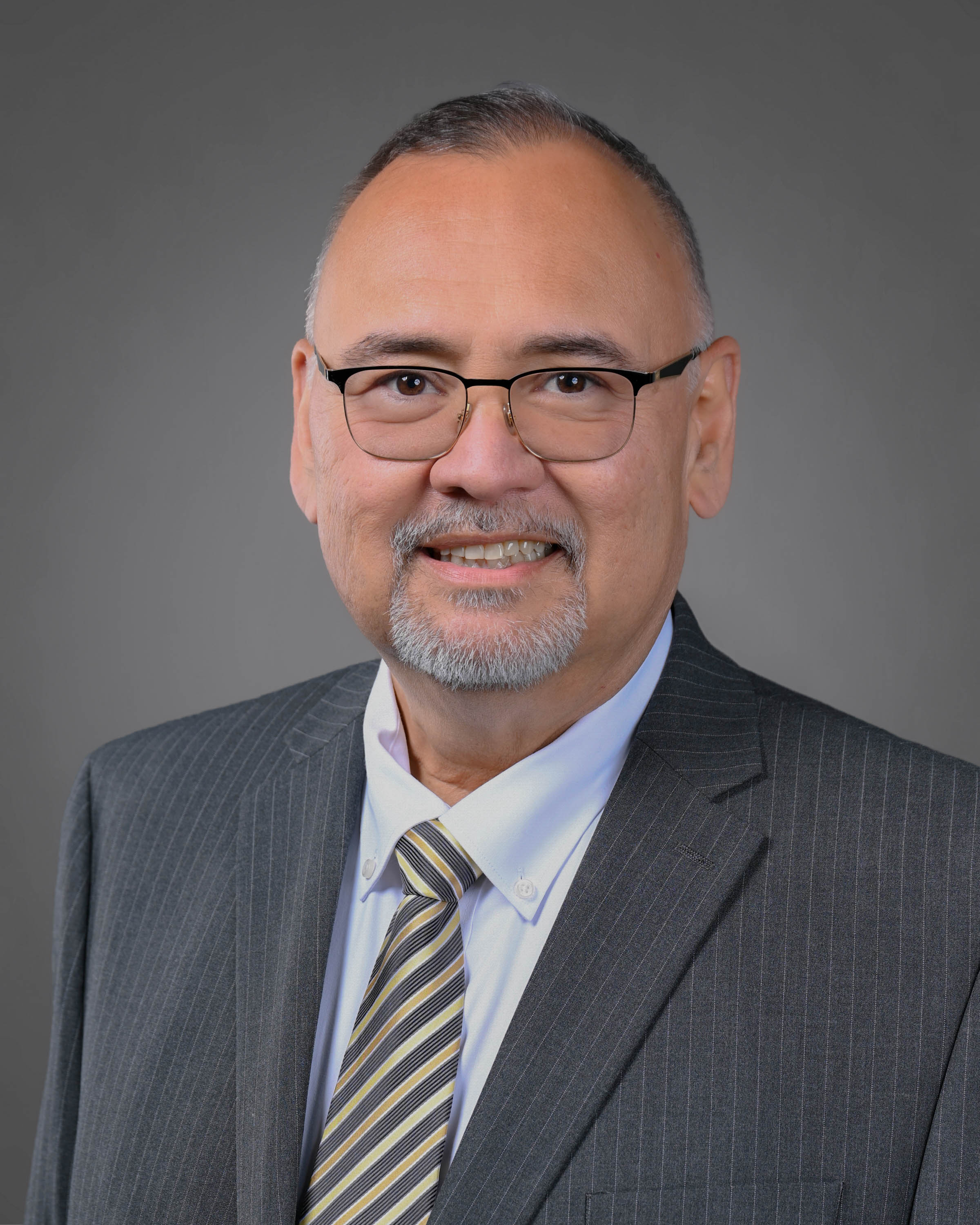 Man with glasses and goatee in a stripped grey suit